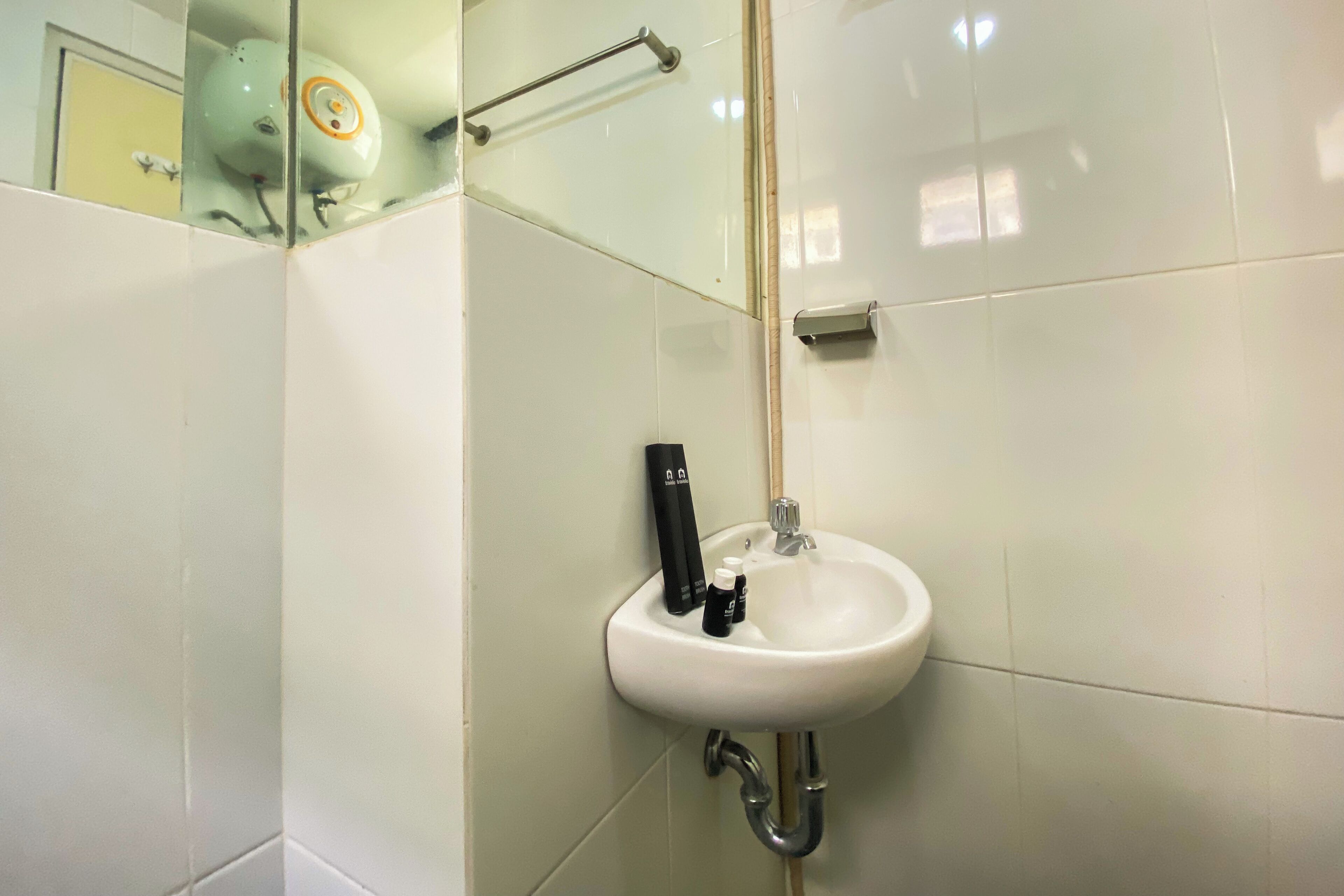 Ein Badezimmer mit einem weißen Waschbecken, einem Handtrockner und einer Glastrennwand.