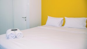 Habitación de hotel con una cama, dos almohadas y dos toallas enrolladas sobre la cama.