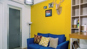 Una habitación con un sofá azul, una pared amarilla y una mesa de madera.