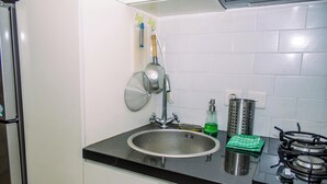 Una cocina con un lavamanos de acero inoxidable, una estufa a gas y un grifo empotrado.