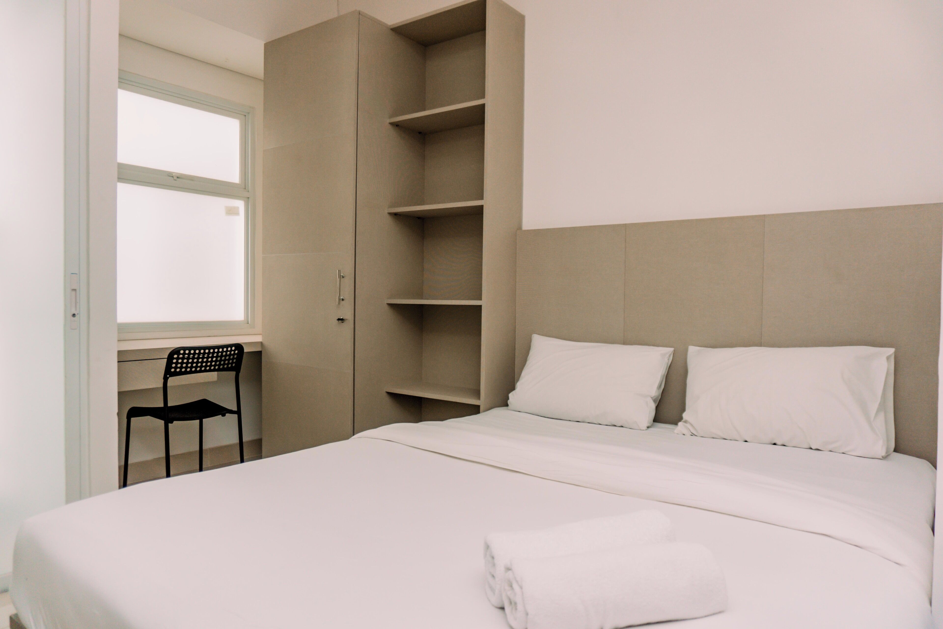 Un dormitorio con cama, una silla y estanterías empotradas.