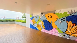 A spacious room with wooden flooring and a colorful mural on the wall. - Studio Patraland Urbano Apartment (Bekasi)