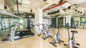 A gym with stationary bikes, treadmills, and weight machines. - Studio Patraland Urbano Apartment (Bekasi)