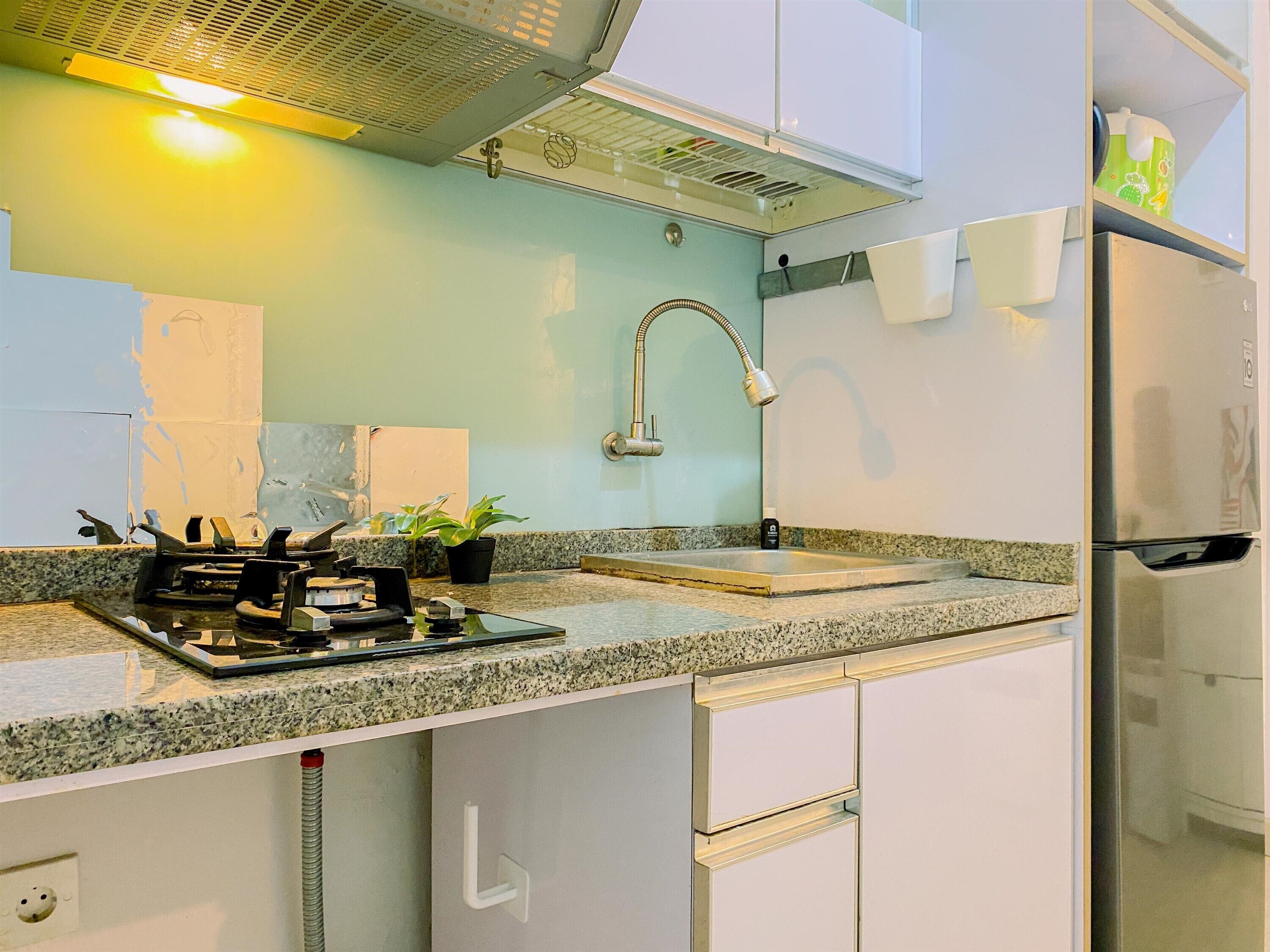 A kitchen with white cabinets, a stainless steel refrigerator, a granite countertop, a gas stove, and a sink with a modern faucet.