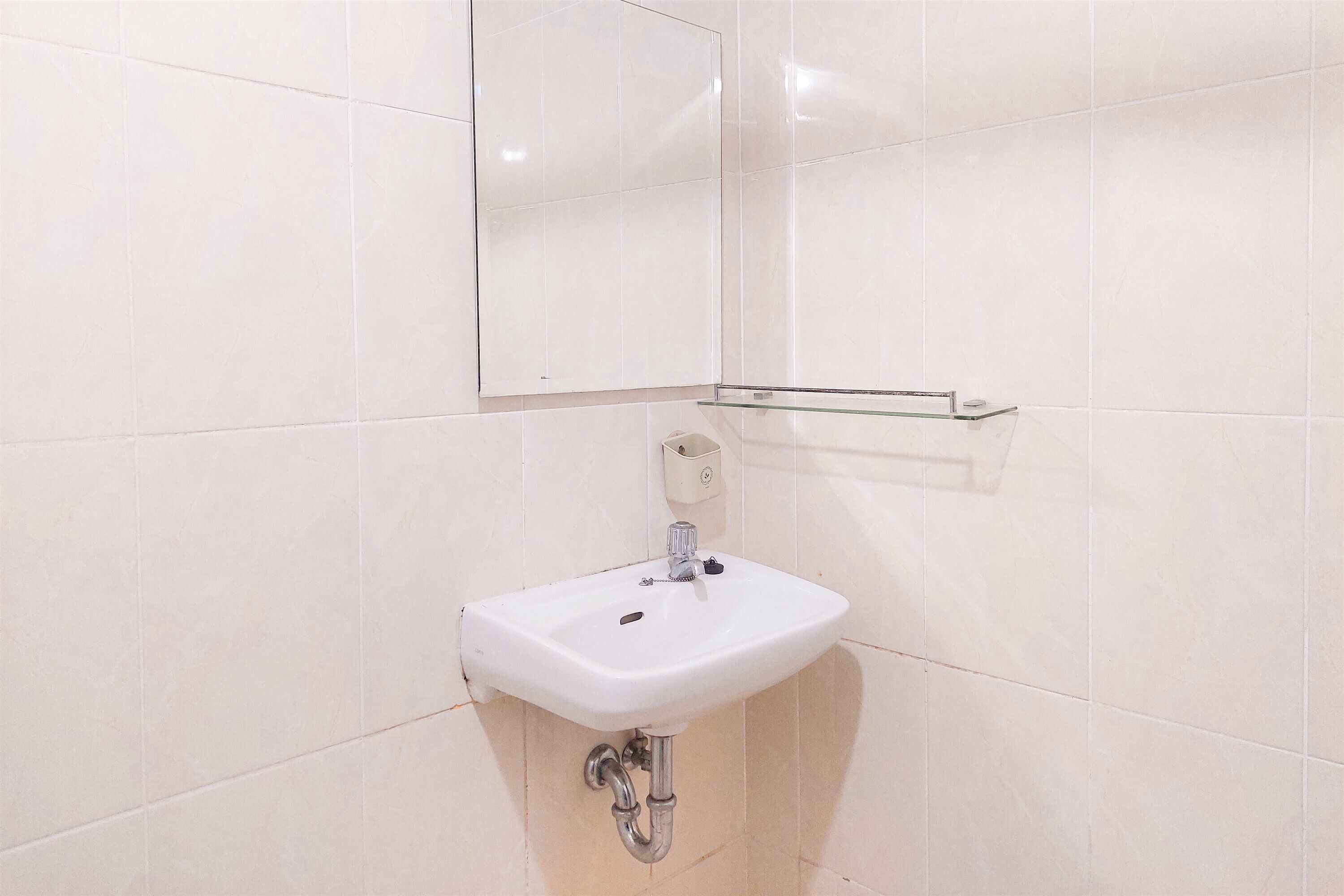 Un bagno con un lavandino bianco, uno specchio e un dispenser di sapone a parete.