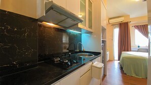 A compact kitchen with a black countertop, stainless steel sink, and a range hood.