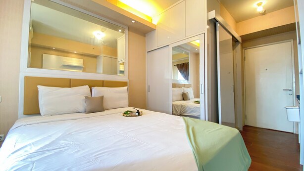 A hotel room with a large bed, a mirror, and a wardrobe.