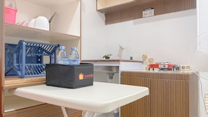 A compact kitchen with a white countertop, a blue dish rack, a black storage box, and a wooden cabinet. - Good Place And Comfortable 2Br At Green Pramuka City Apartment (Jakarta)