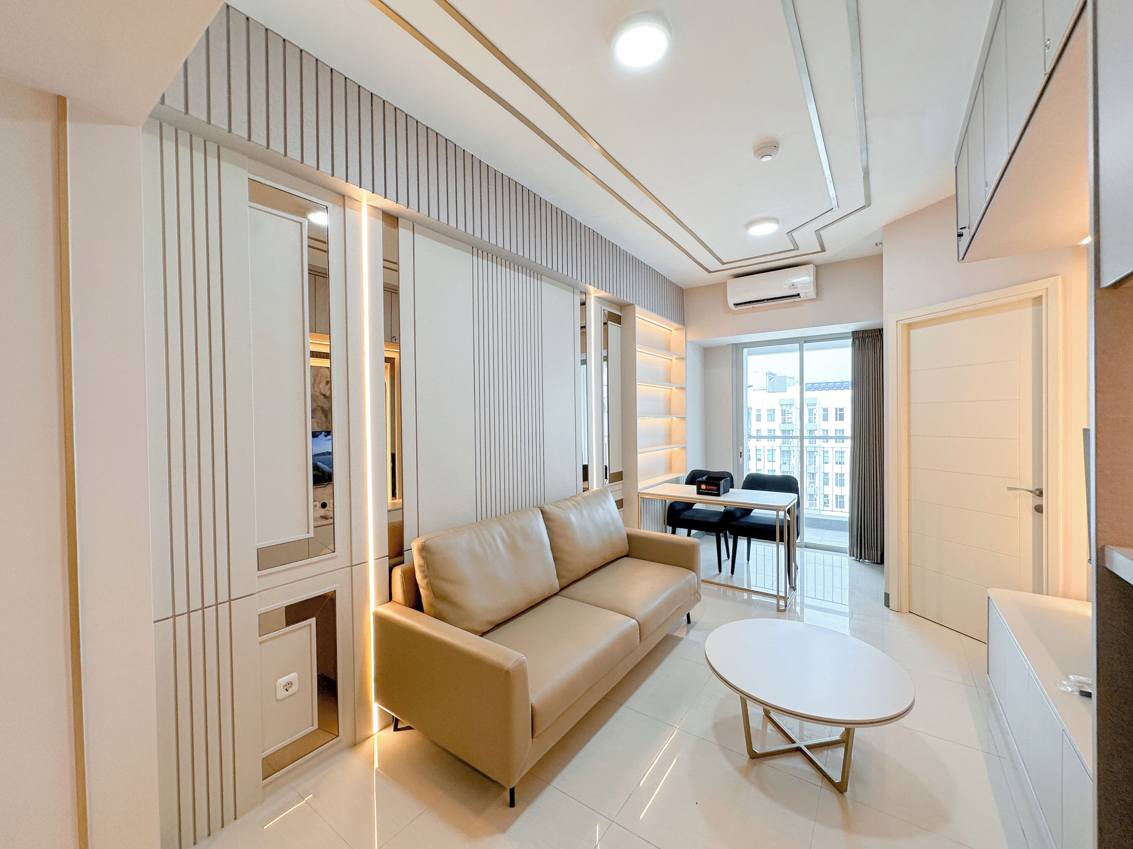 A modern living room with a beige sofa, a small round table, and a built-in bookshelf.