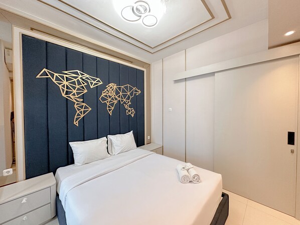 Um quarto moderno com arte de parede de mapa mundi, uma cama bem arrumada e um guarda-roupa.