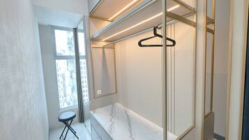 A modern bathroom with a marble vanity, a hanging shower, and a view of the city through a large window.