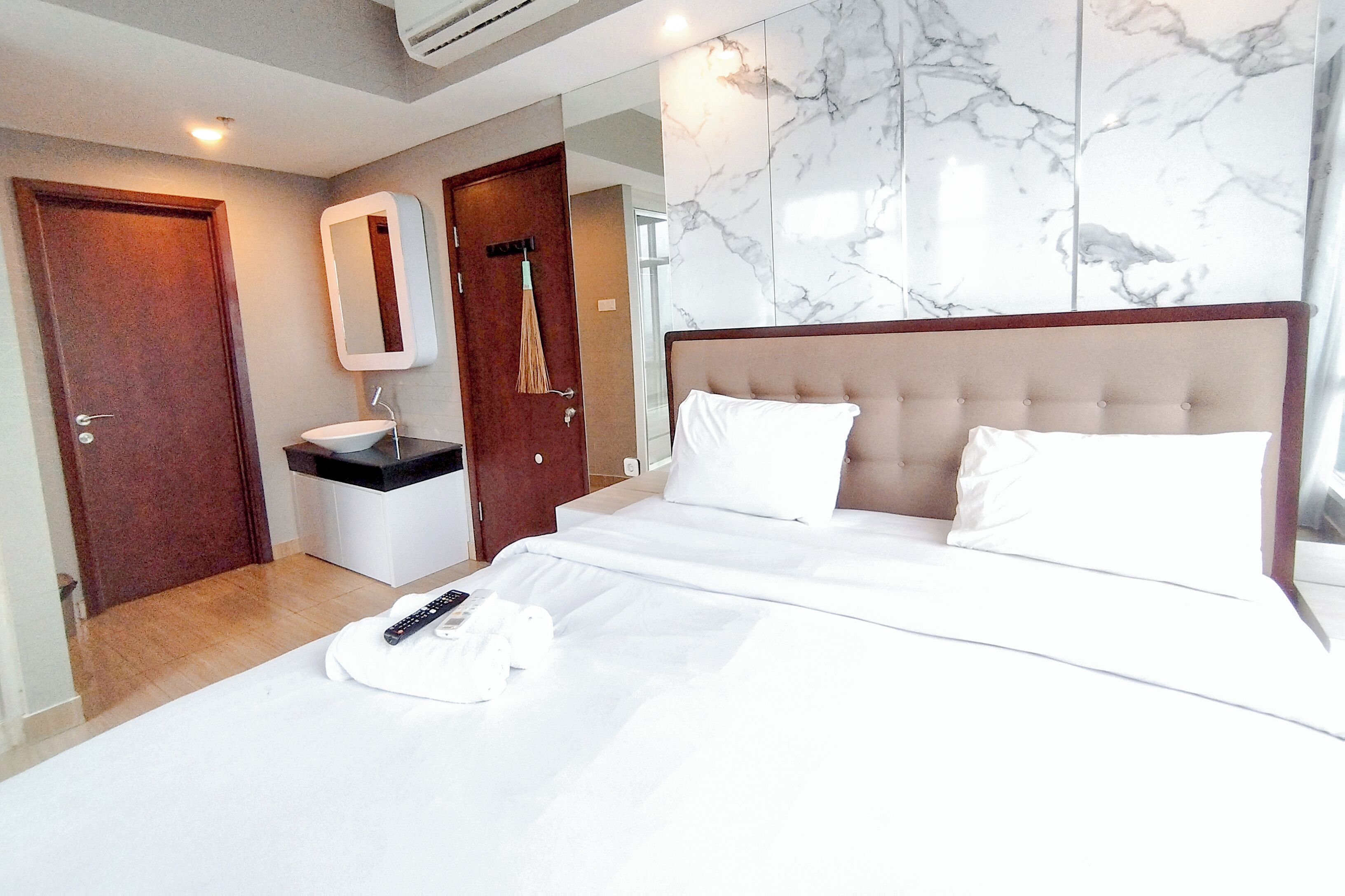 A hotel room with a bed, a bathroom, and a marble wall.