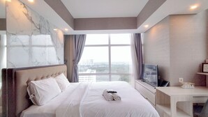 Una habitación de hotel con una cama grande, televisión y escritorio.