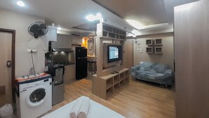 Een knus woongedeelte met een kitchenette, een wasmachine, een flatscreen-tv en een bank.