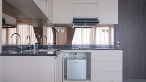 A modern kitchen with a built-in refrigerator, stainless steel appliances, and a dark countertop. - Great Choice 2Br At Bintaro Icon Apartment (South Tangerang)