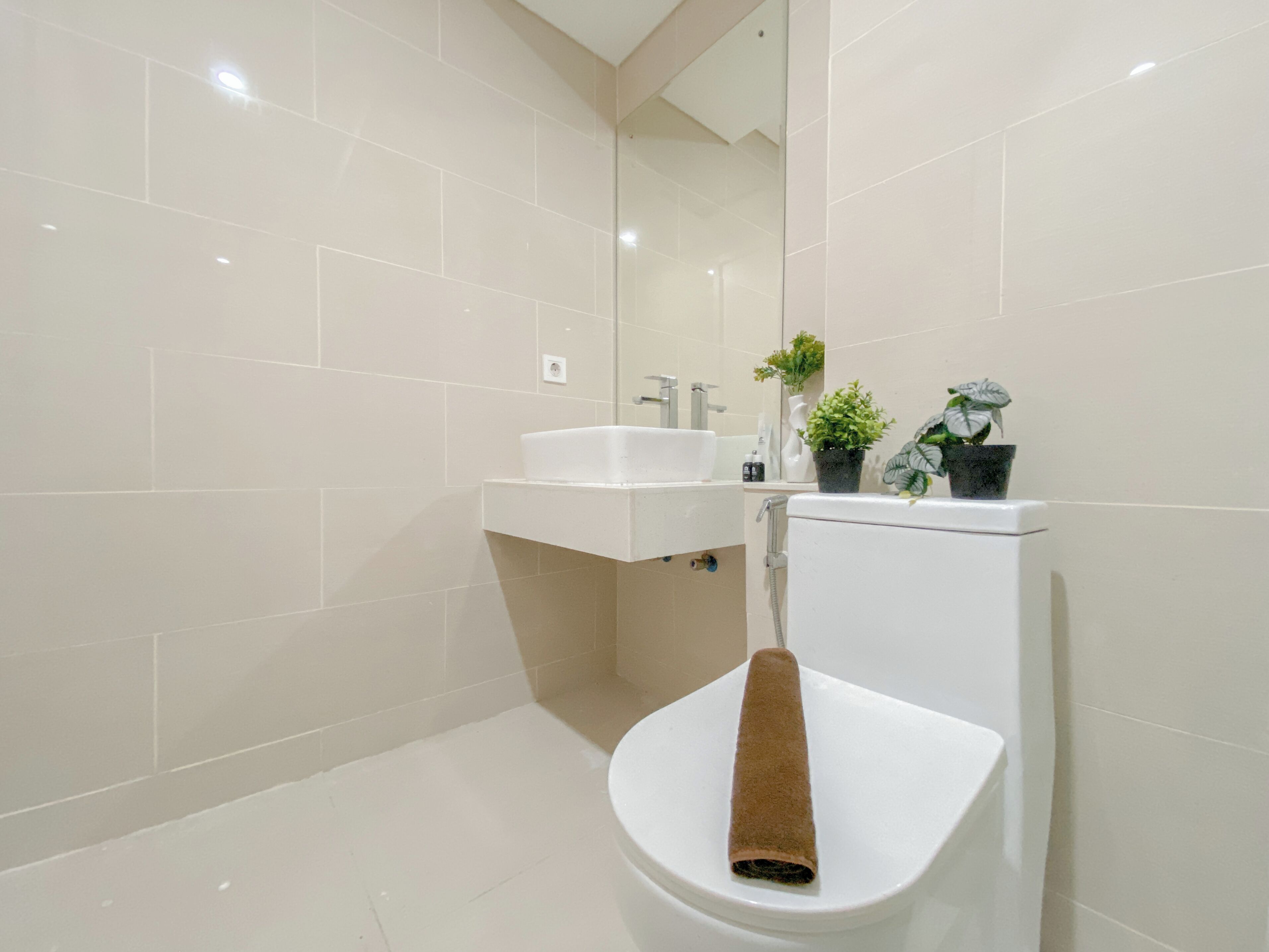 A modern bathroom with a toilet, sink, and two potted plants.