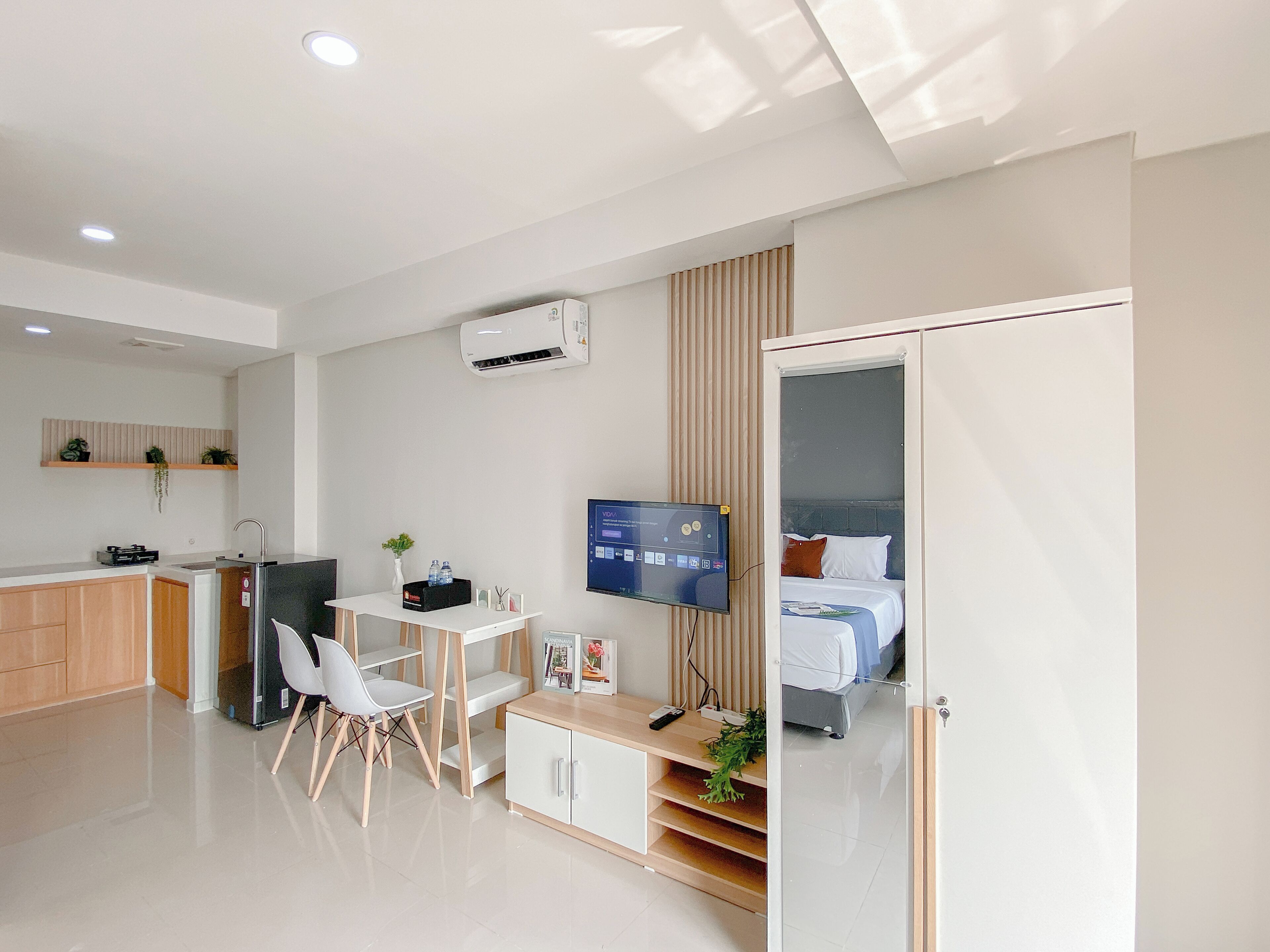 Une chambre d’hôtel moderne équipée d’un lit, d’un bureau avec une chaise, d’une télévision et d’un coin cuisine.