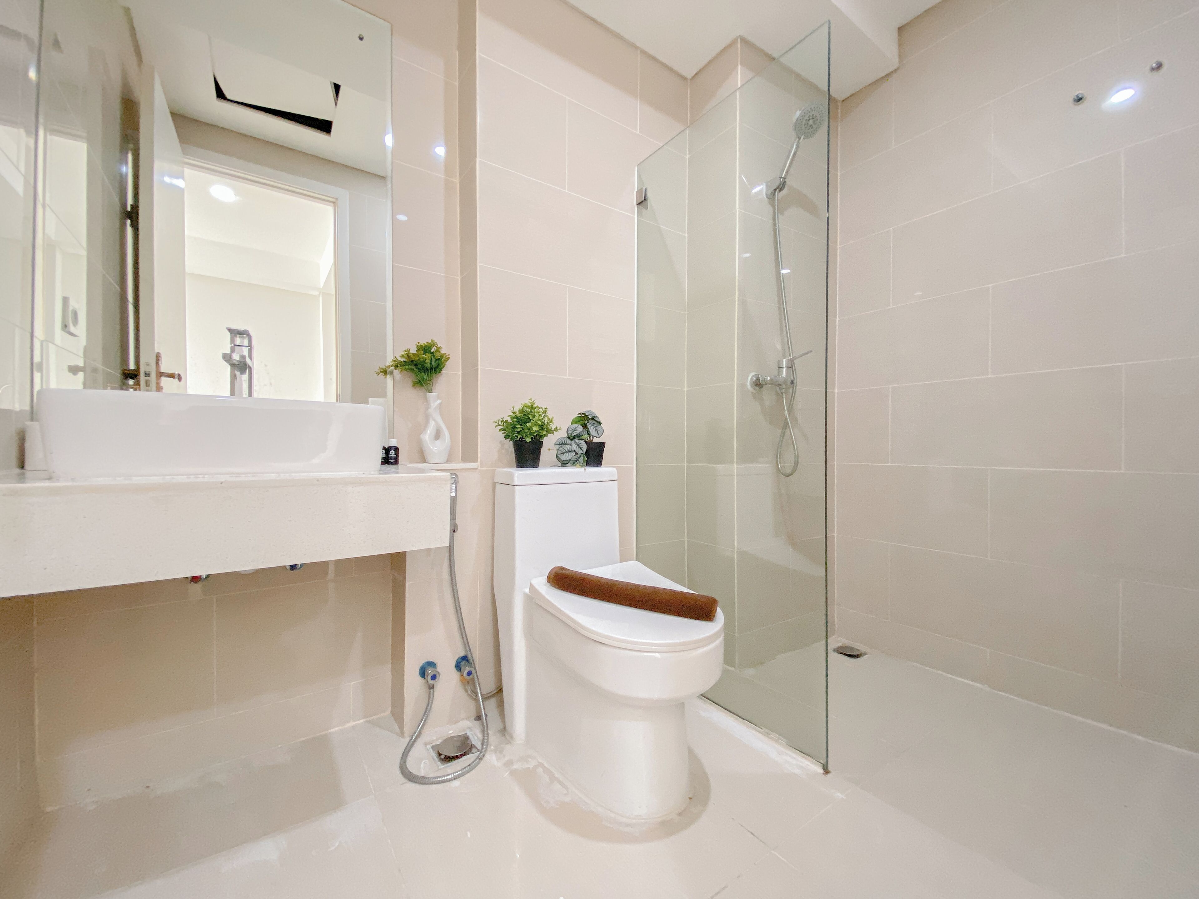 A modern bathroom with a glass-enclosed shower, a white sink, and a toilet with a wooden seat.