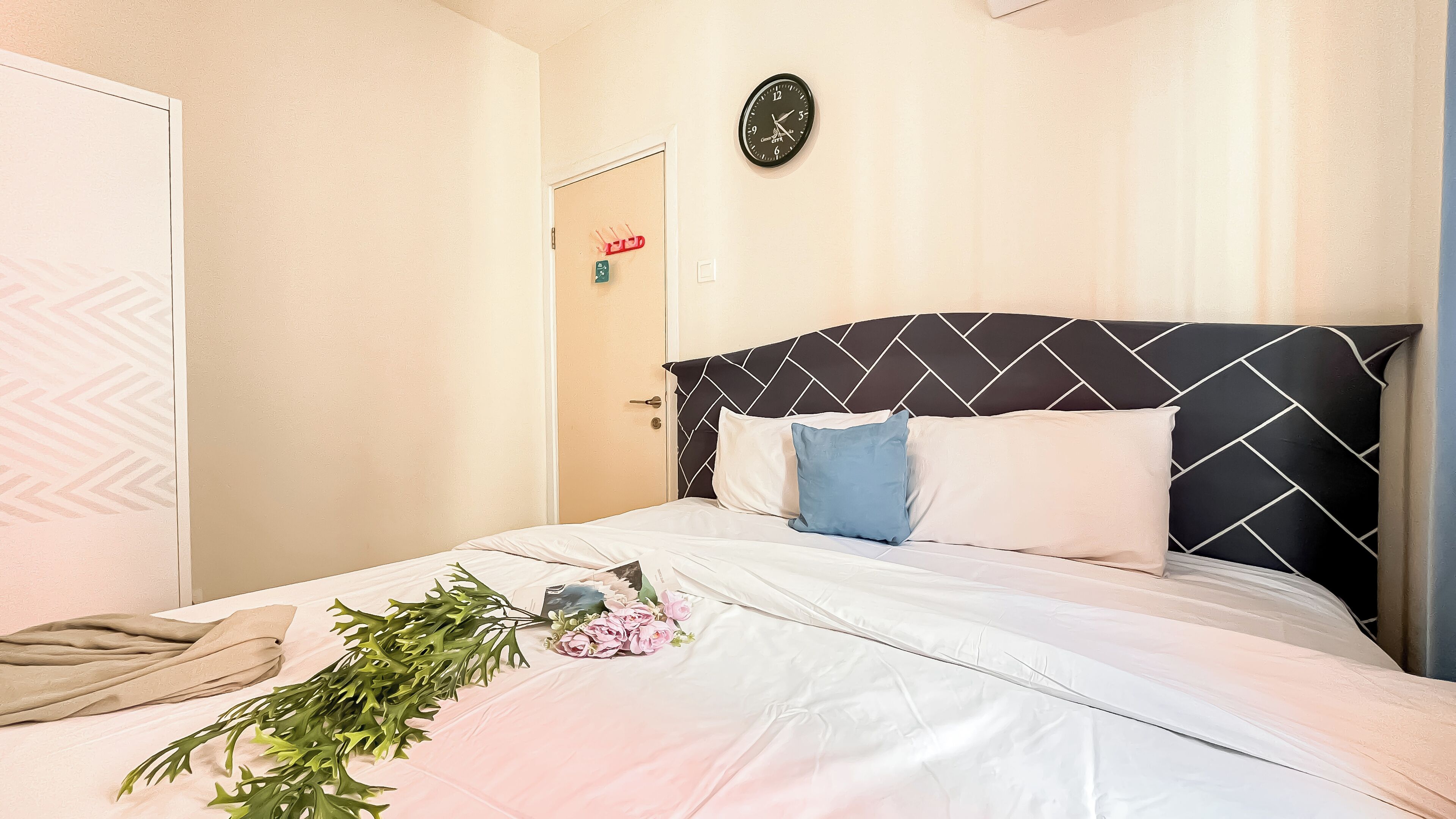 A neatly made bed with white linens, a black and white headboard, and decorative pillows.