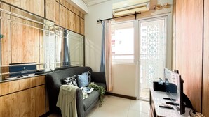 A compact living space with a sofa, a small table, a mirror, and a sliding door to the outside. - Best Deal And Warm 2Br Apartment Green Pramuka City (Jakarta)