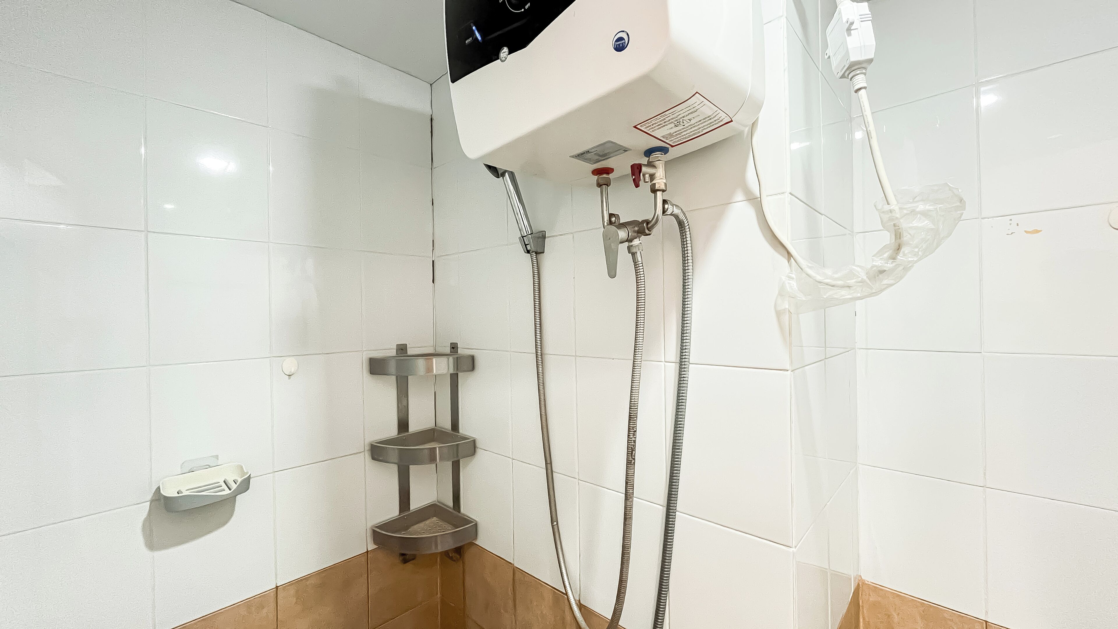 A shower area with a handheld showerhead, a wall-mounted faucet, and a handheld basin.