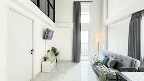 Un soggiorno moderno con un divano grigio, un tavolino e una TV a parete.