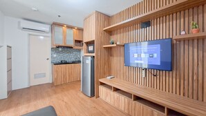 A modern kitchen with wooden cabinetry, a built-in TV, and a refrigerator.