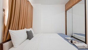 A hotel room with a bed, a bedside table, a mirror, and a wardrobe.