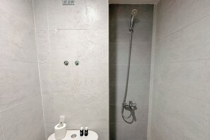 A bathroom with a shower, toilet, and two bottles of toiletries on the sink. - Good Deal Stunning Studio (No Kitchen) At Taman Melati Surabaya Apartment (Surabaya)