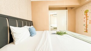 A hotel room with a bed, a headboard, a door, and a wall with a tree decal.