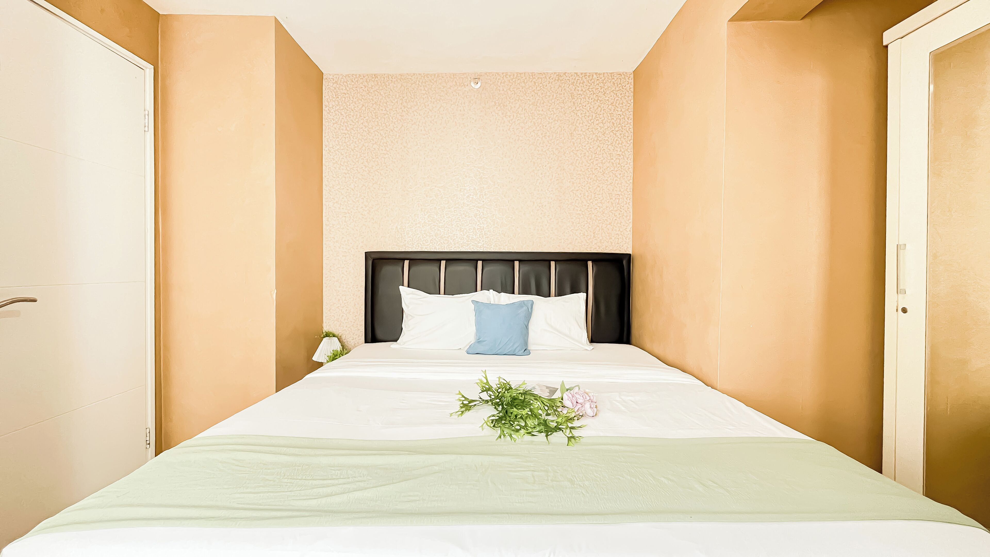 Una camera d'albergo con un letto, un comodino e una lampada fissata al muro.