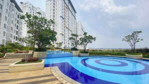 A swimming pool with a blue spiral design, surrounded by a tiled deck and greenery.