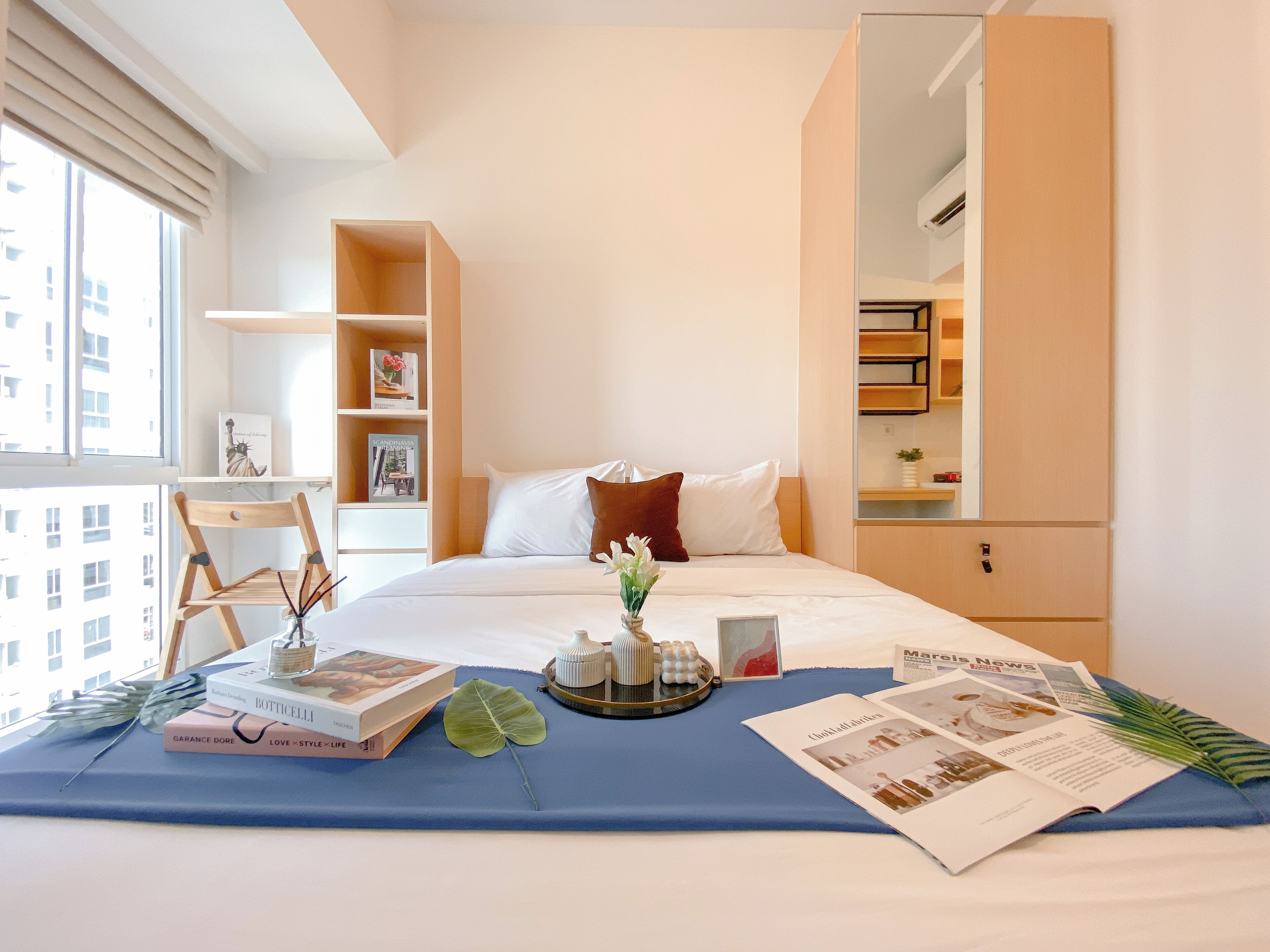 Una camera d'albergo con un letto, una scrivania, una sedia e una libreria.