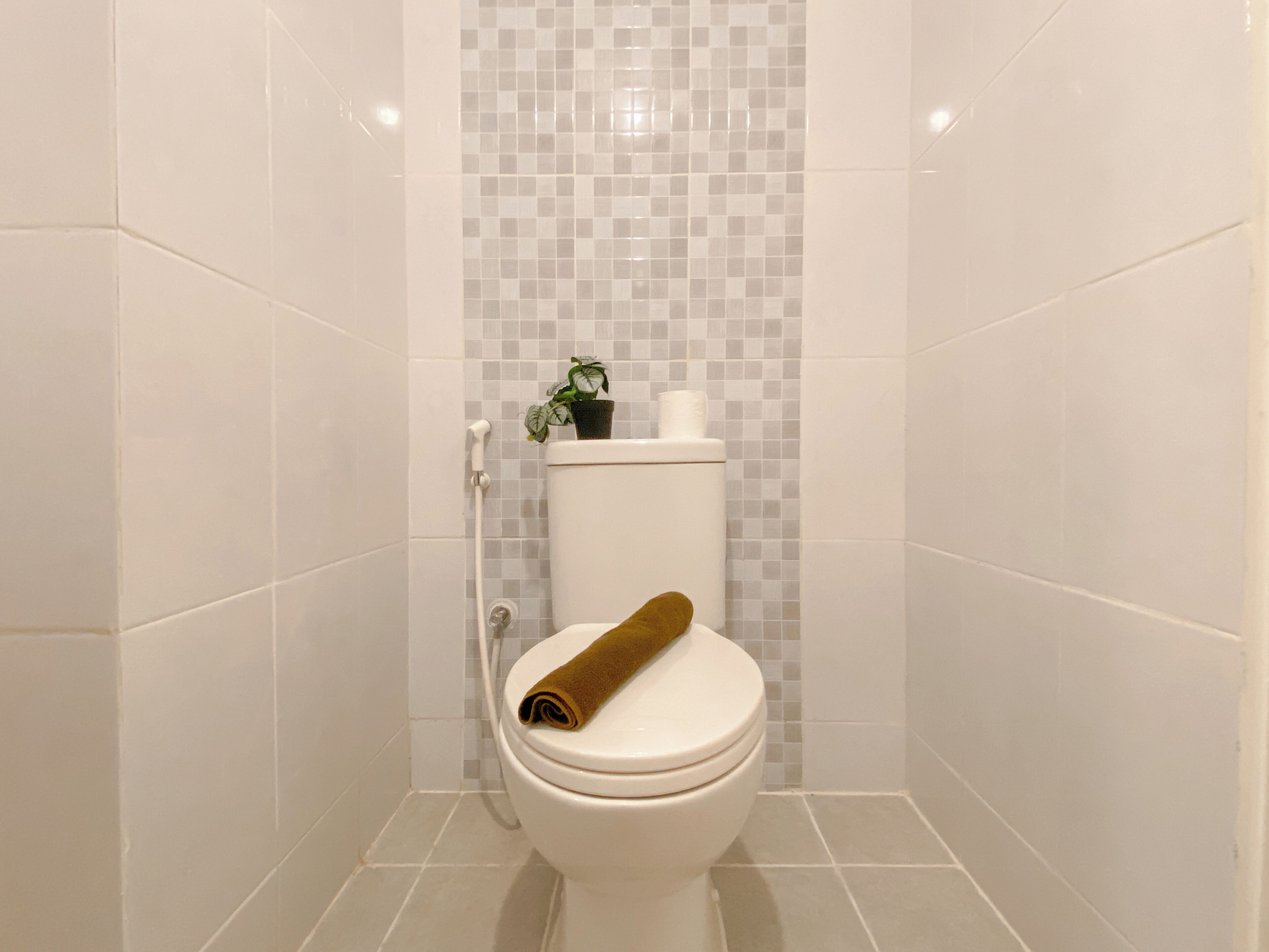 A bathroom with a toilet, a shower, and a tiled wall with a checkered pattern.