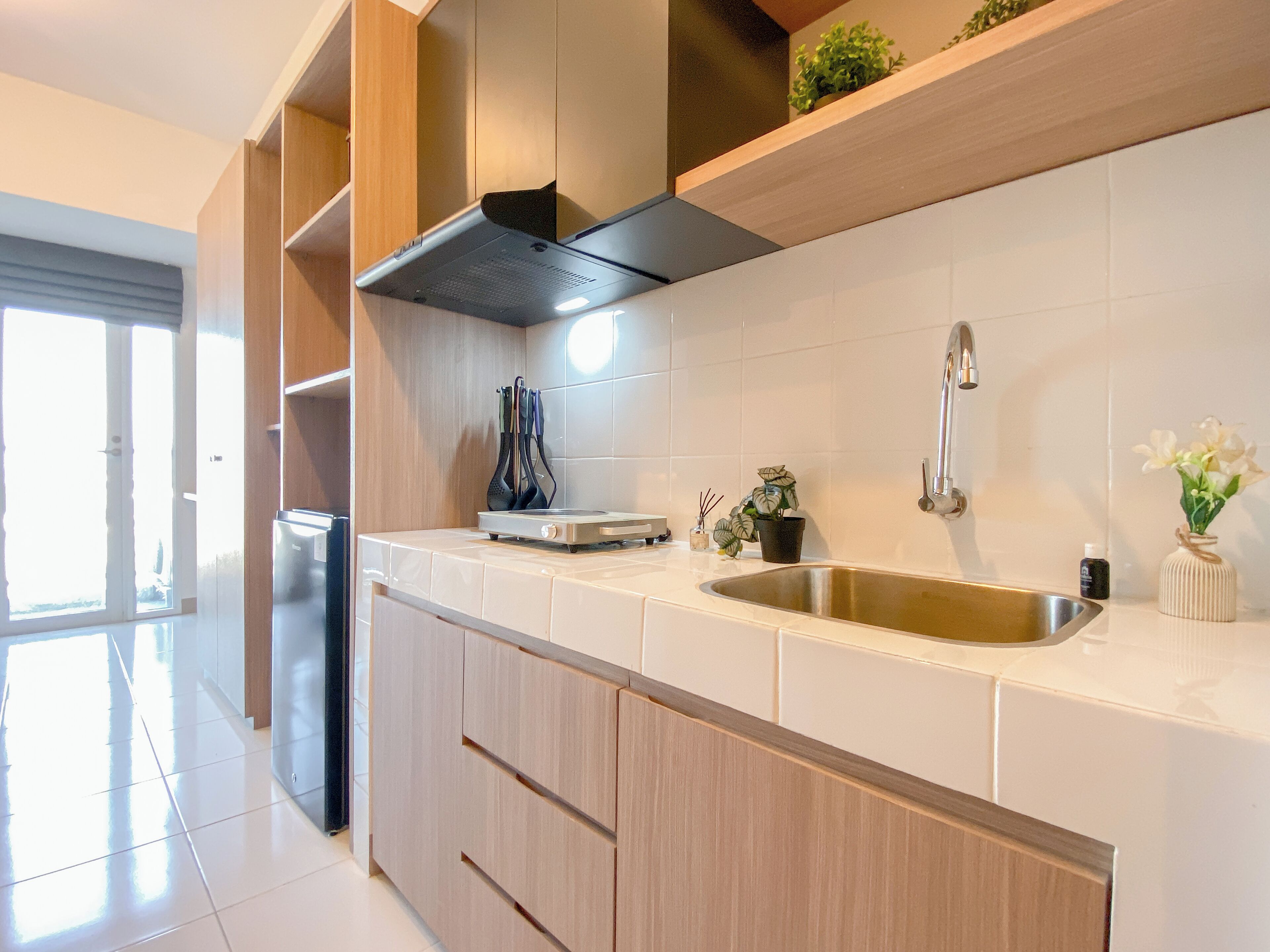 A modern kitchen with a stainless steel sink, wooden cabinets, and a black range hood.