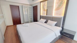 A neatly made bed with white linens, a bedside table with a drawer, and a large mirror above the bed. - 2Br Minimalist And Simply At Grand Sungkono Lagoon Apartment (Surabaya)