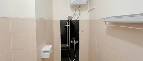 A small, enclosed shower area with a built-in heater, a handheld showerhead, and a wall-mounted toilet.