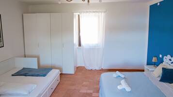 A bedroom with a bed, a wardrobe, a window with curtains, and a blue wall.