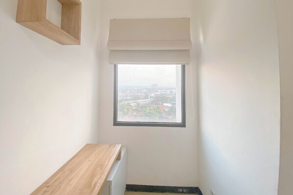 Una habitación estrecha con un ventanal pequeño, un banco de madera y un radiador.