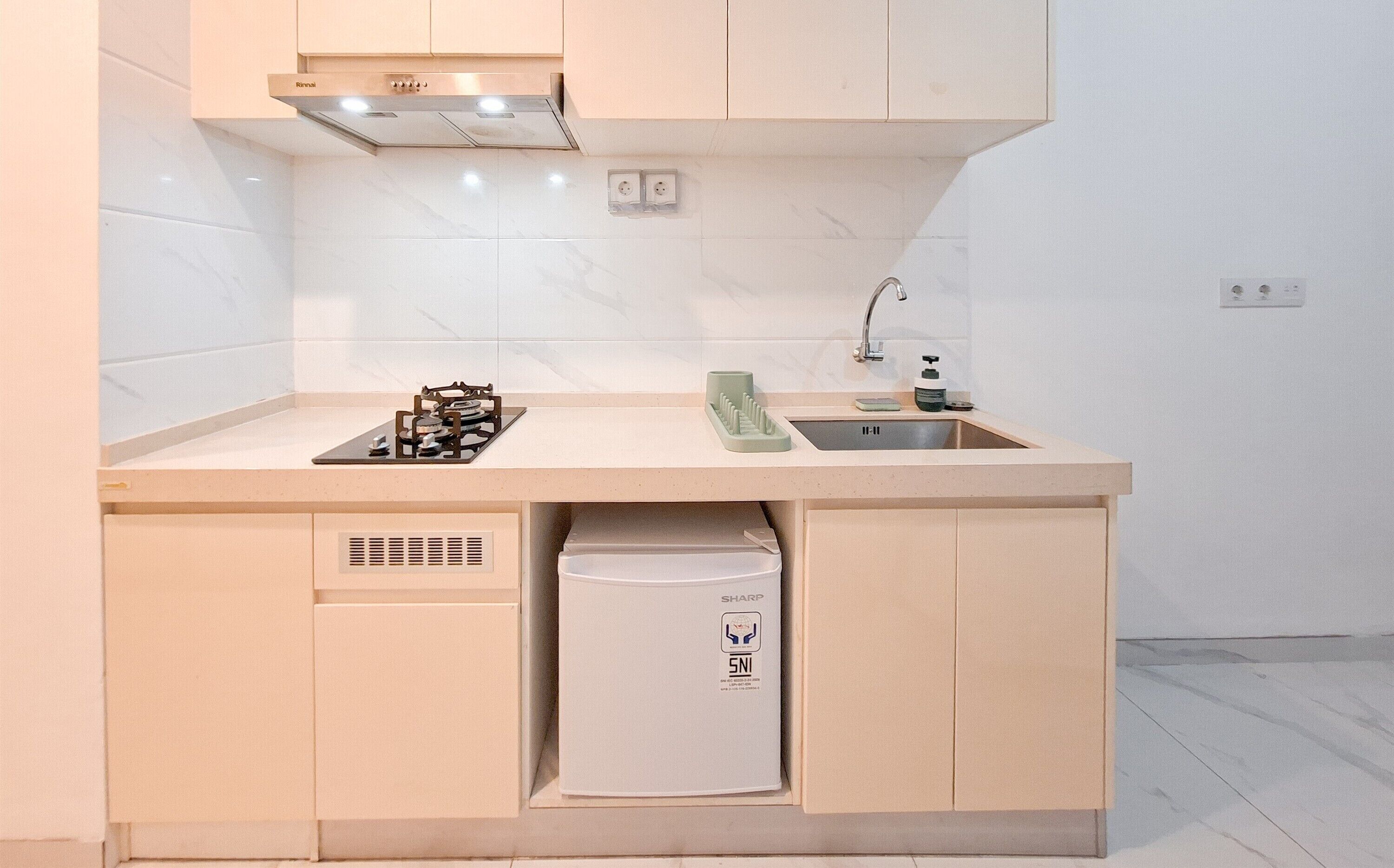 A compact kitchen with a gas stove, sink, and a built-in refrigerator.
