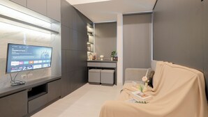 Ett modernt vardagsrum med en platt-TV, en soffa, ett soffbord och ett litet sidobord med en vas och en bok.