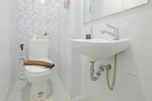 Une salle de bain avec des toilettes, un lavabo et un miroir.