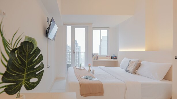 Una camera d'albergo moderna con un letto grande, una TV a parete e un balcone con vista sulla città.