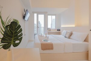 Una habitación de hotel moderna con una cama grande, un televisor montado en la pared y un balcón con vista a la ciudad.