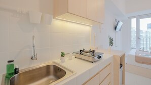 Una cucina moderna con lavello in acciaio inossidabile, piano cottura a gas ed elementi contenitori bianchi.