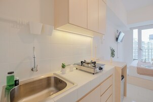 Una cocina moderna con un lavamanos de acero inoxidable, estufa a gas y armarios blancos.