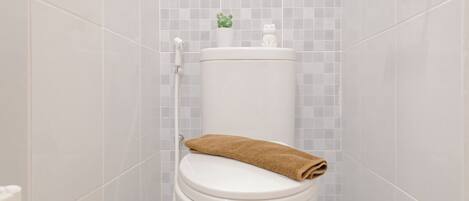 A white toilet with a brown towel on top, a small potted plant, and a handrail.