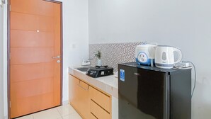 Eine kleine Küche mit einem Kühlschrank, einer Kaffeemaschine und einer Mikrowelle.
