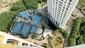 Vue aérienne d’un hôtel doté de plusieurs piscines, d’un grand bâtiment situé à côté de l’espace piscine et d’un jardin paysager bien entretenu.