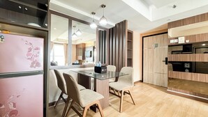 Une cuisine moderne avec une table à manger en verre, des meubles de rangement en bois et des luminaires suspendus.